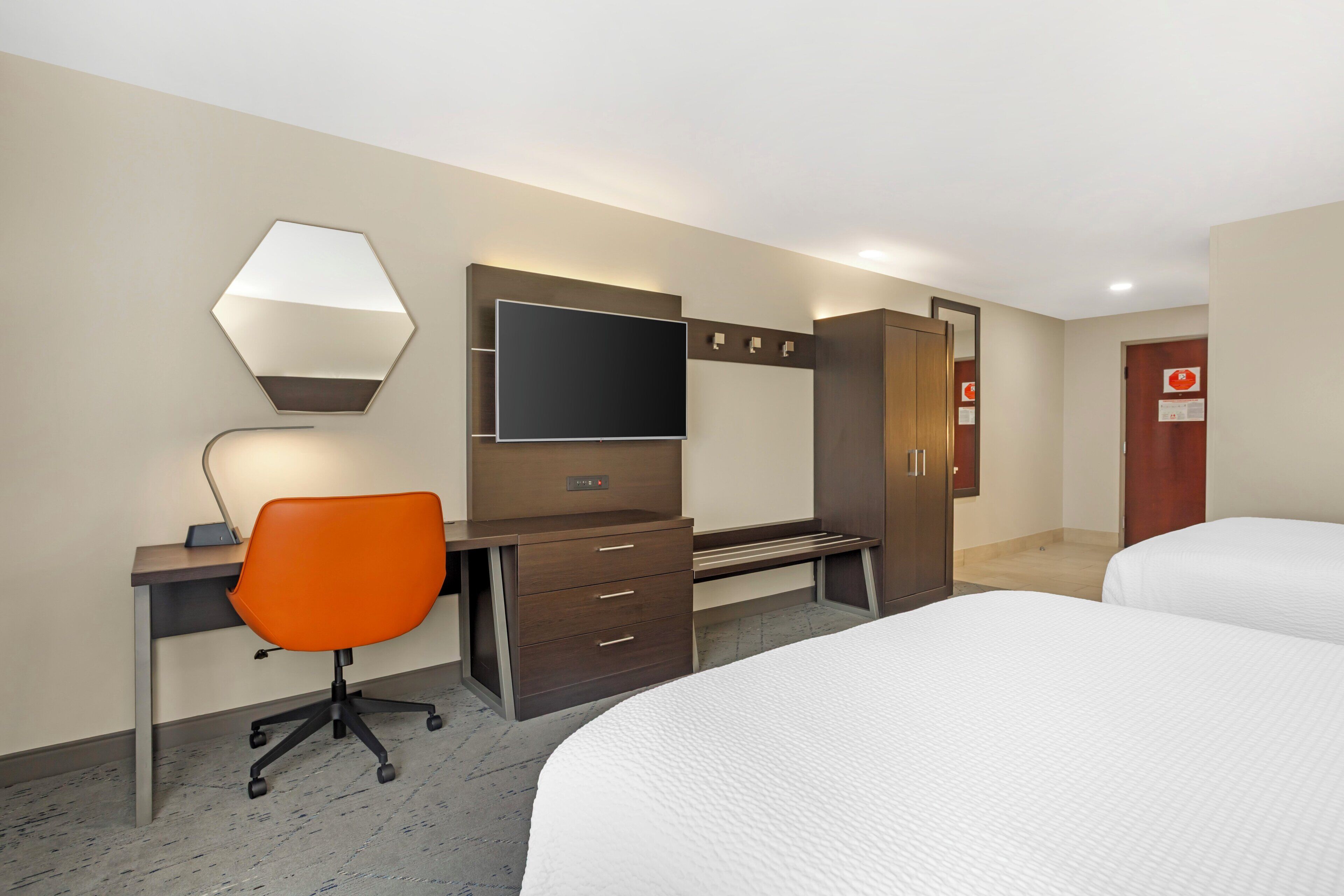 Una habitación de hotel con escritorio, silla, cama, armario y televisor.
