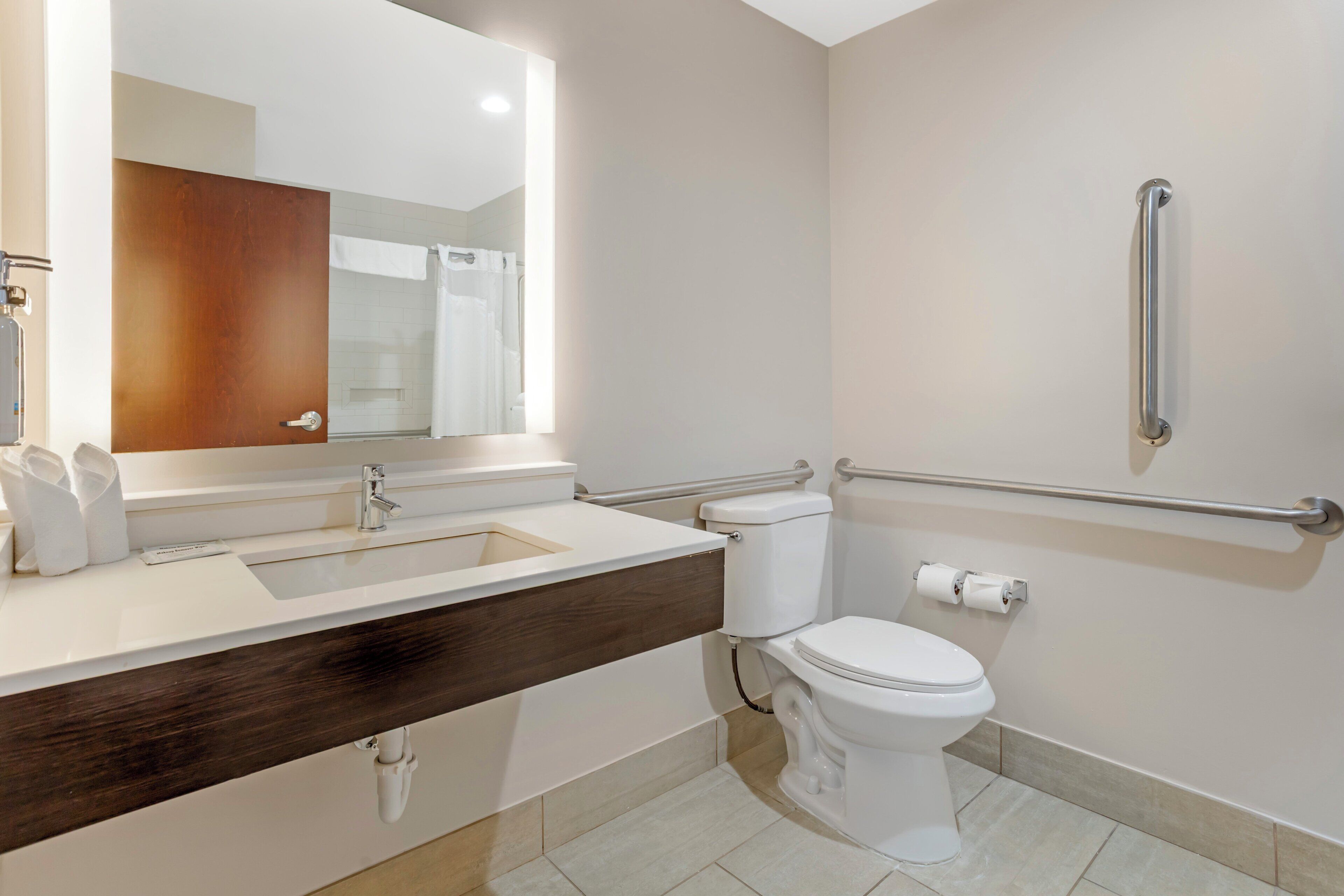 A modern bathroom with a white sink, a mirror, a toilet, and a shower area.