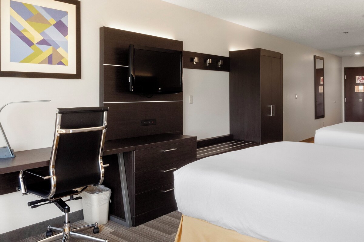 A hotel room with a bed, a desk, a chair, a television, and a wardrobe.