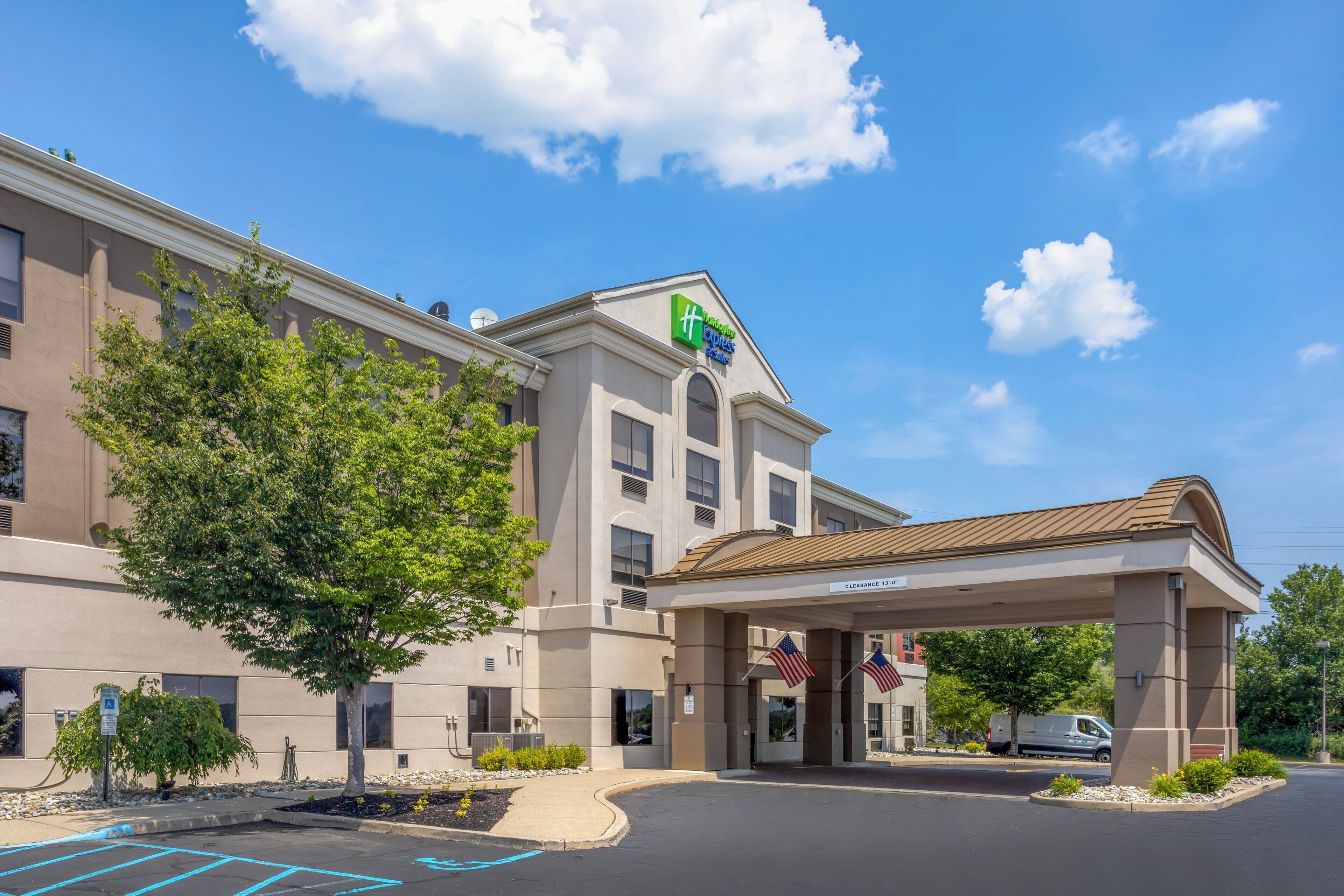 A hotel with a clear sky, a covered entrance, and American flags.