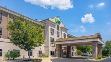 A hotel with a clear sky, a covered entrance, and American flags.