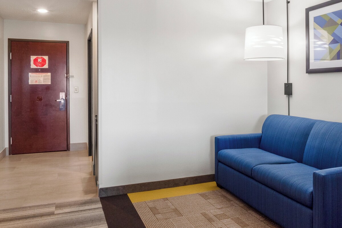 A hallway with a blue sofa, a door with a stop sign, and a framed abstract painting on the wall.