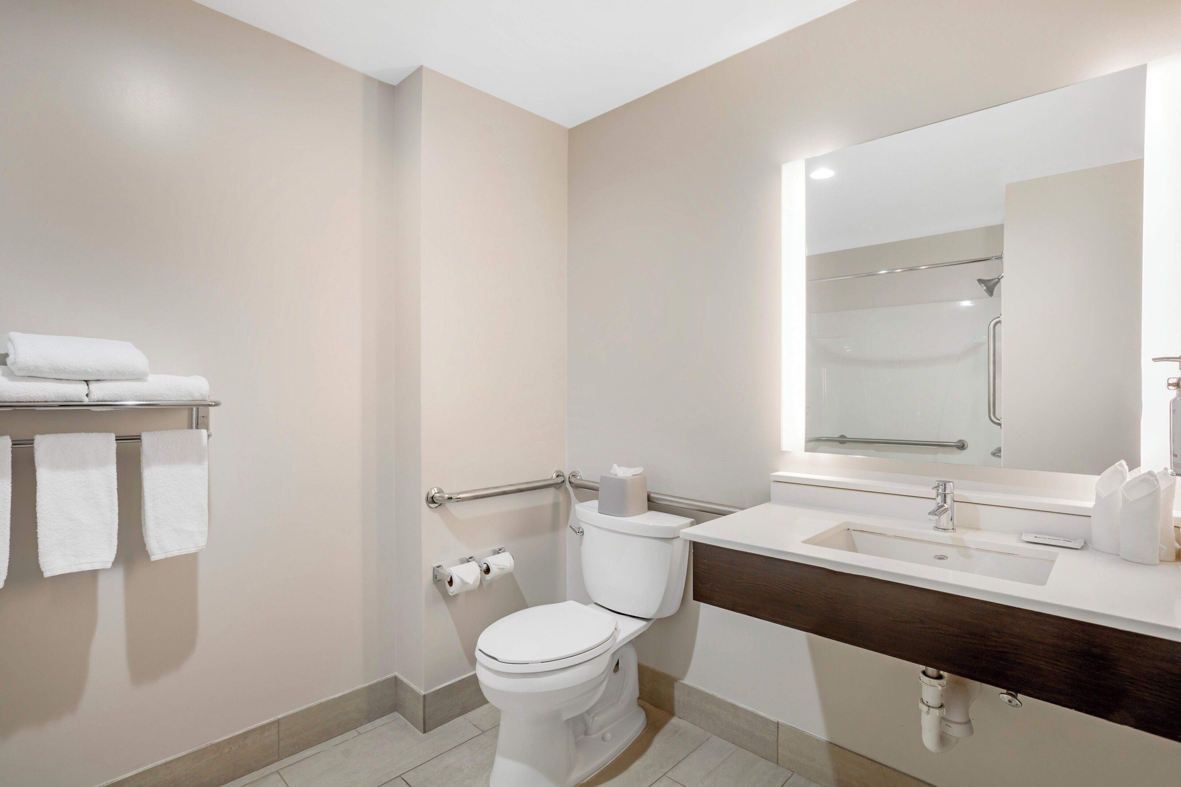A modern bathroom with a toilet, sink, and mirror.