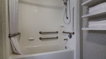 A white bathtub with grab bars, a showerhead, and a towel rack.