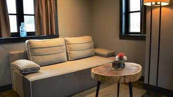 Un salon moderne avec un canapé, une table basse ronde en bois et un lampadaire.