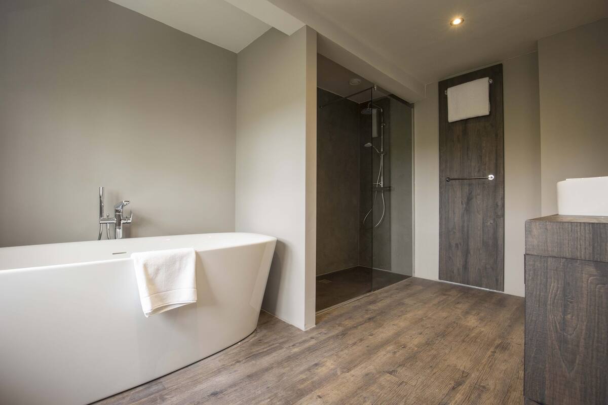 A modern bathroom with a freestanding bathtub, a glass-enclosed shower, and a wooden vanity.