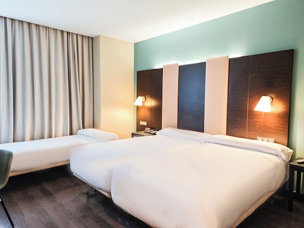 A hotel room with a large bed, two bedside tables, a chair, and a curtain. - AZZ Pamplona Norte (Berrioplano)