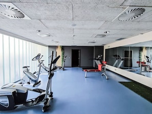 Un gimnasio con equipamiento de ejercicio, piso azul y un espejo grande.
