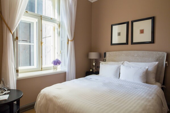 A hotel room with a large bed, a bedside table with a lamp, and two framed pictures on the wall. - Hotel Telegraaf, Autograph Collection (Tallinn)