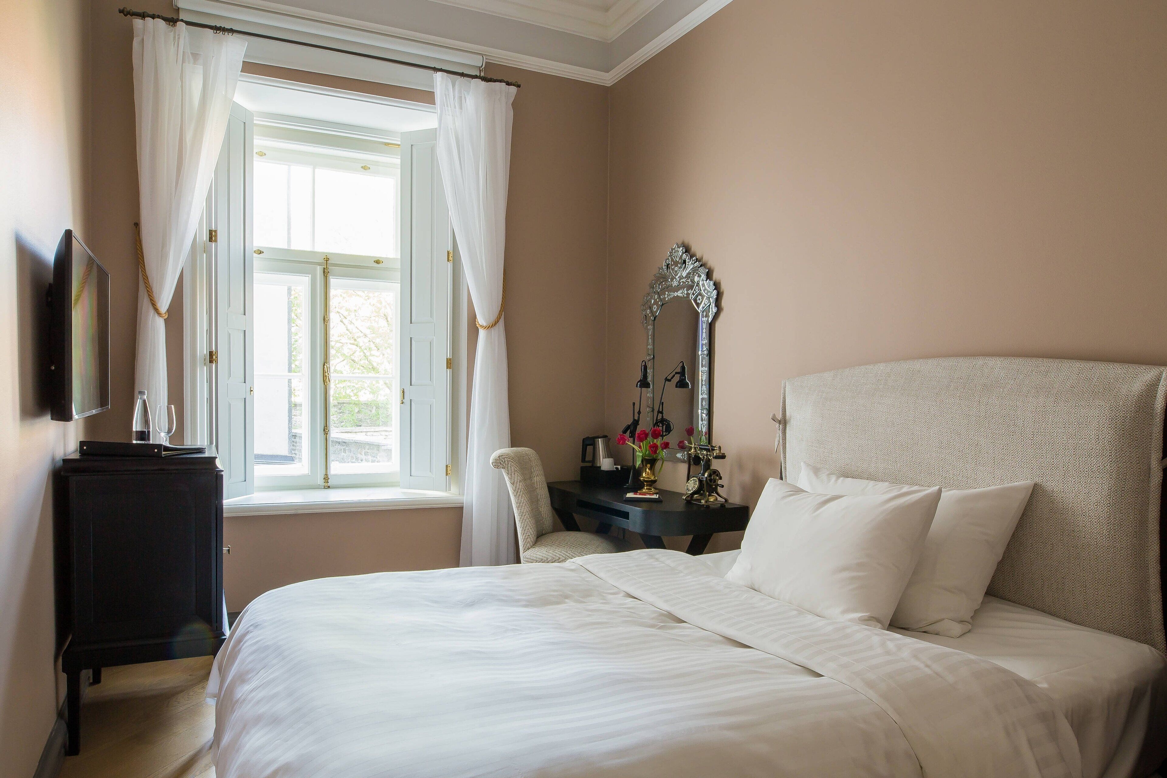 Une chambre à coucher avec un grand lit, un bureau doté d’un miroir et une chaise.