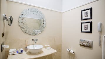 A bathroom with a round mirror, sink, and two framed pictures on the wall.