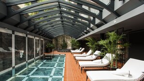 A modern indoor pool area with lounge chairs and potted plants. - Hotel Telegraaf, Autograph Collection (Tallinn)
