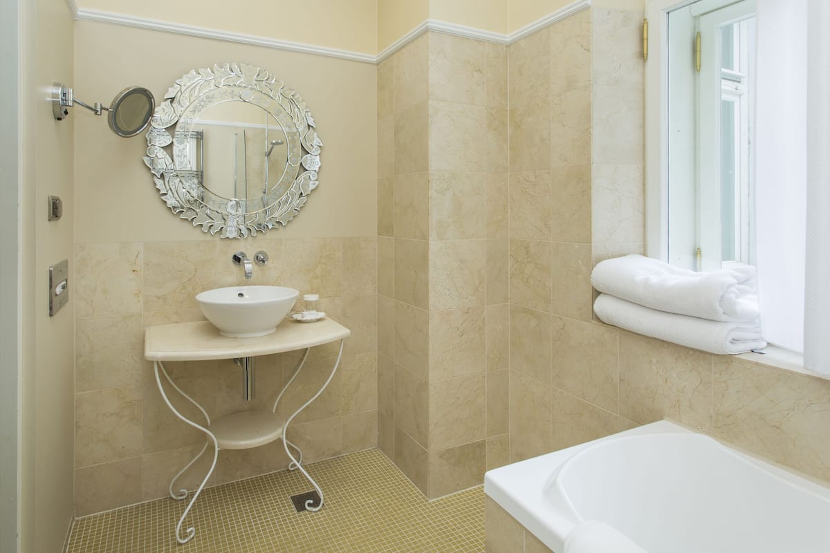 A bathroom with a sink, mirror, and bathtub.