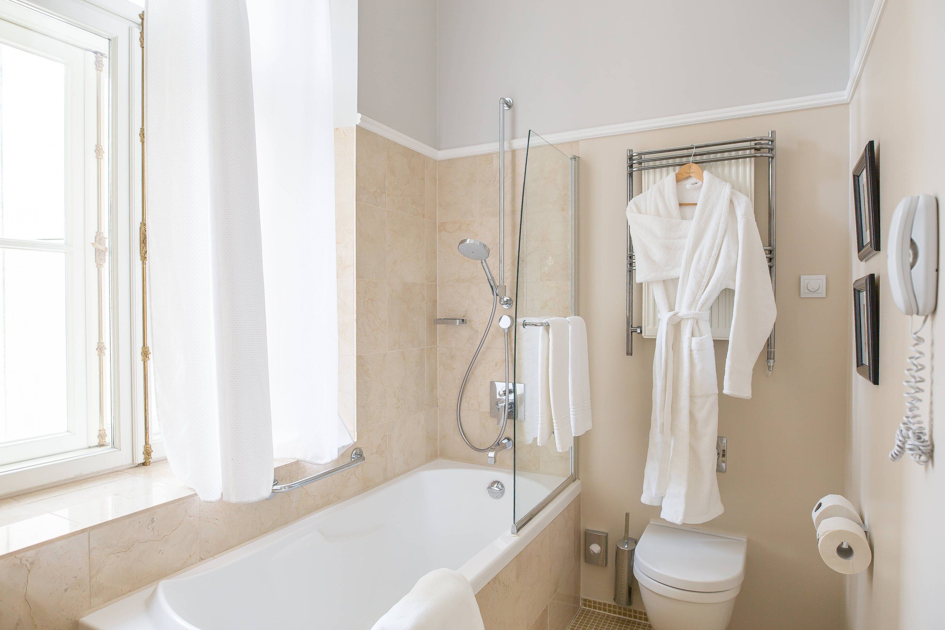 A bathroom with a bathtub, a shower, a toilet, and a towel rack.