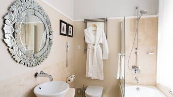 A bathroom with a large ornate mirror, a white sink, a toilet, a bathtub, and a shower.