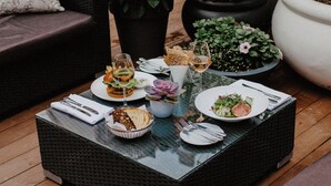 An outdoor dining area with wicker furniture, a variety of dishes, and potted plants. - Hotel Telegraaf, Autograph Collection (Tallinn)