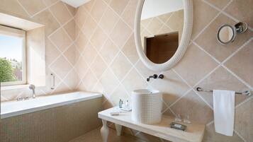 Une salle de bain avec une grande baignoire, un meuble-lavabo avec un évier, un miroir et un porte-serviettes.