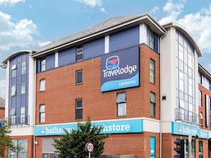 A Travelodge hotel with a modern brick facade, large windows, and a sign for a bathstore. - Travelodge Camberley (Camberley)