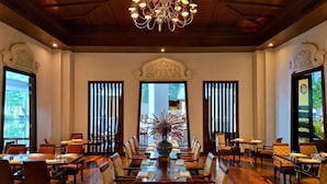 A spacious dining area with a chandelier, wooden ceiling, and large windows.
