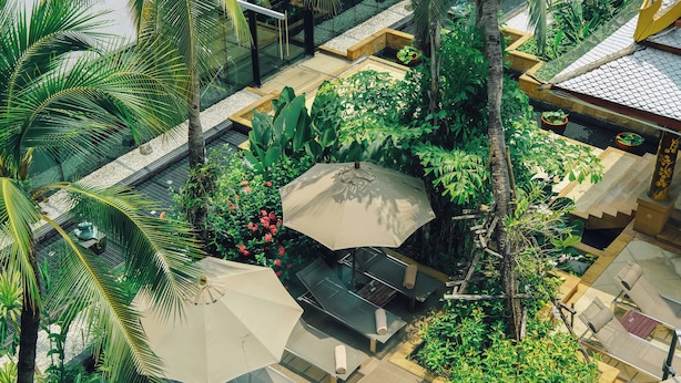 An aerial view of a resort with outdoor seating areas, palm trees, and lush greenery.