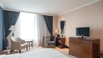 Habitación de hotel con cama, escritorio, silla, televisor y armario.