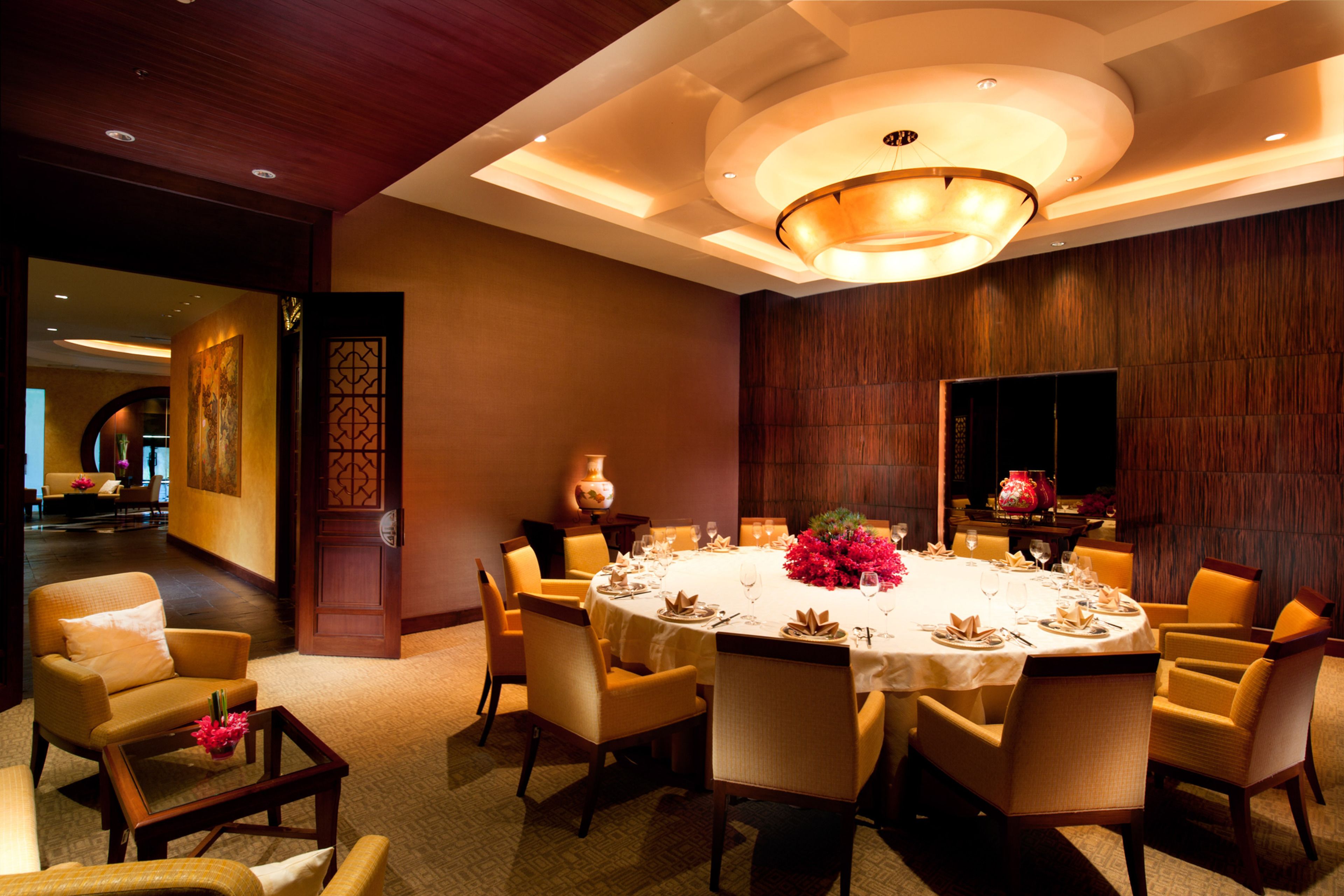 Une salle à manger d’hôtel avec une table ronde dressée pour un repas, entourée de chaises.