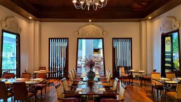 Un comedor espacioso con candelabro, techo de madera y ventanas amplias.