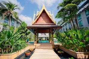 A traditional Thai pavilion with a tiled roof, surrounded by lush greenery and a swimming pool. - Hyatt Regency Bangkok Suvarnabhumi Airport (Bang Phli)