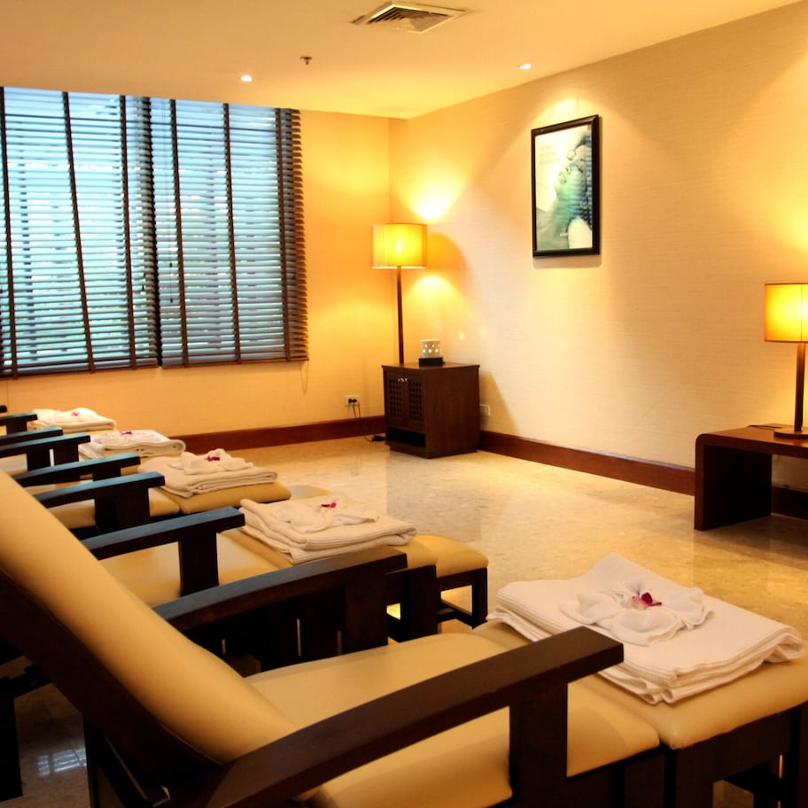 A room with massage chairs, a window with blinds, and two wall-mounted lamps.