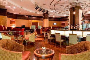 A spacious lobby with comfortable seating, a bar area, and a large screen.