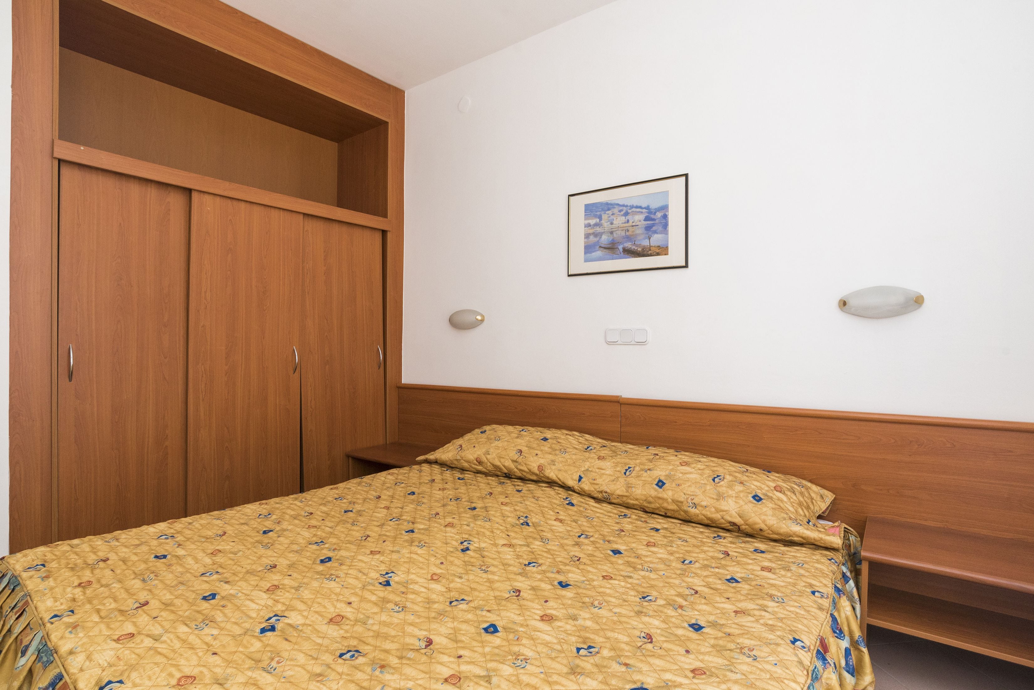 Una camera da letto con un letto, un'armadio in legno e un quadro appeso al muro.