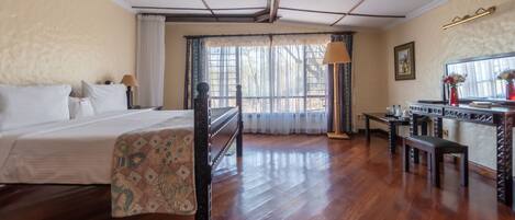 A room with a bed, a desk, a chair, and a window with curtains.