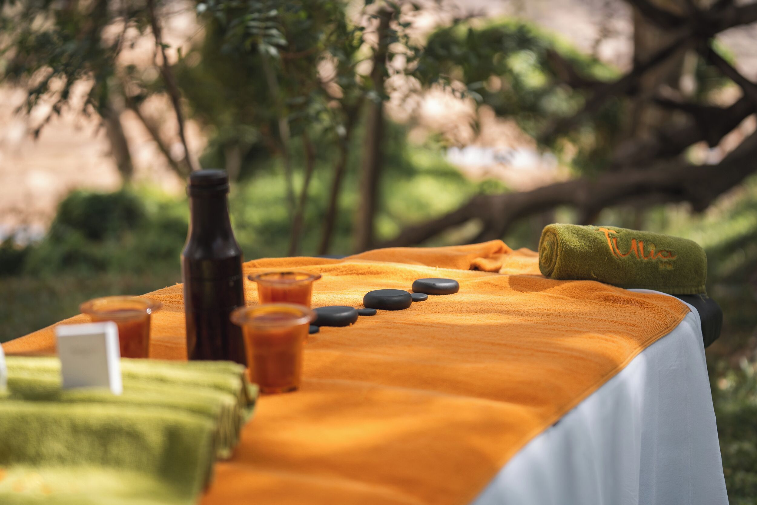 A massage table with stones, towels, and a bottle.