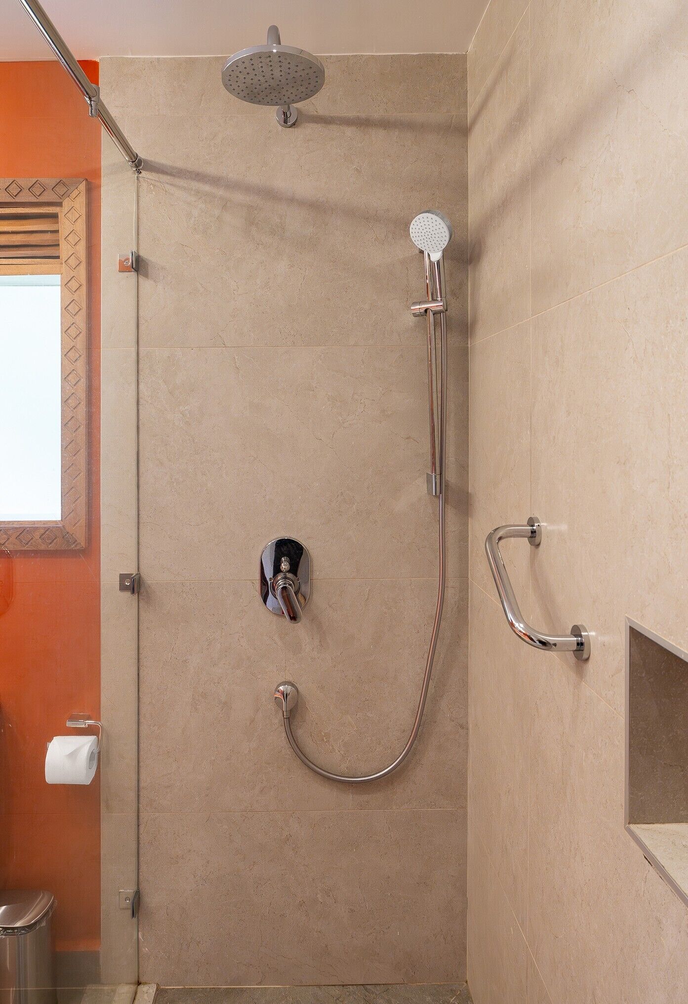 A shower with a handheld showerhead, a wall-mounted faucet, and a grab bar.