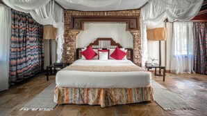 A spacious bedroom with a large bed, a stone accent wall, and draped curtains.