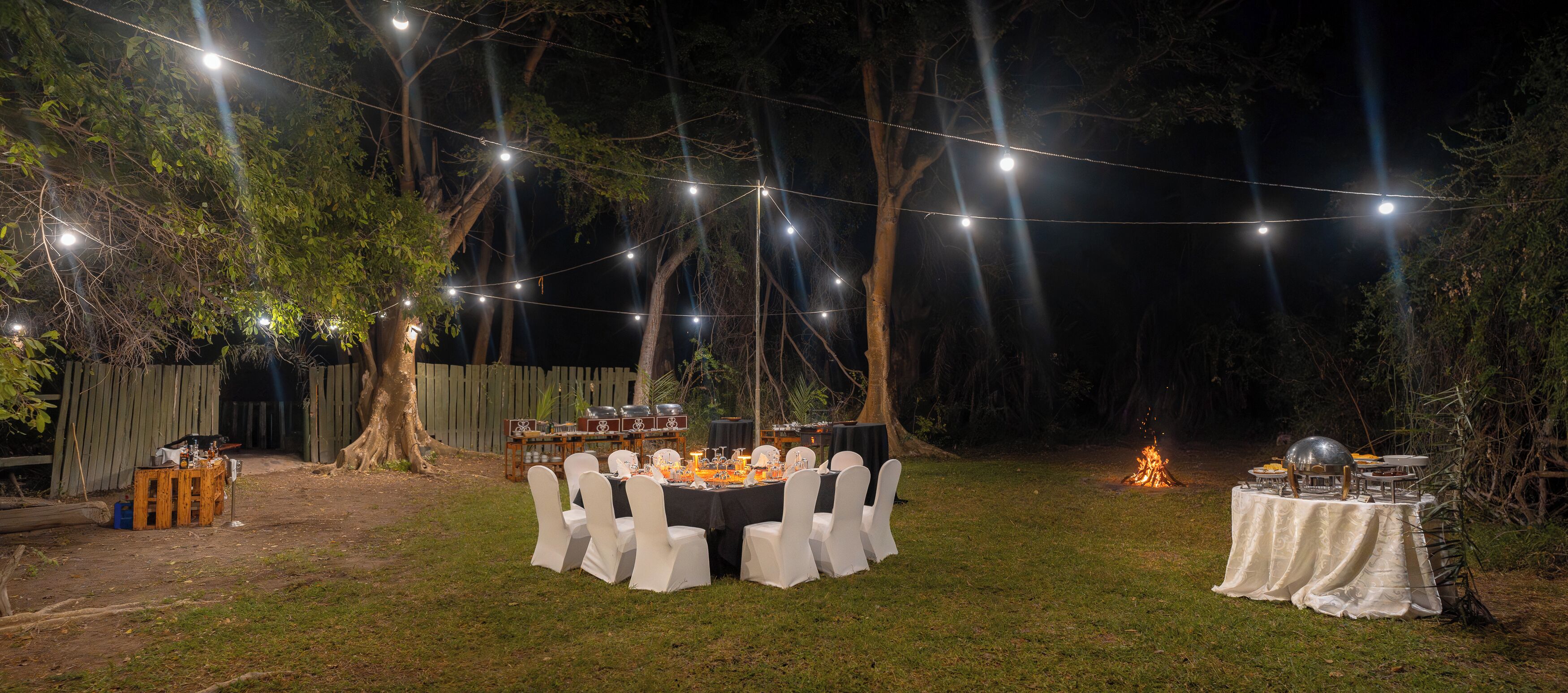 An outdoor dining area with string lights, tables, and chairs.