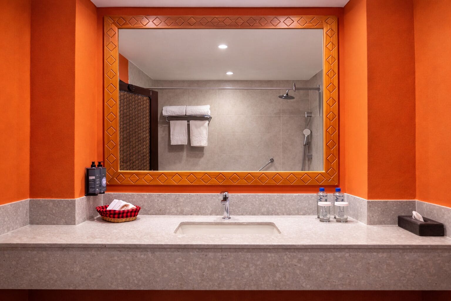 A bathroom with a large mirror, a sink, and a shower.