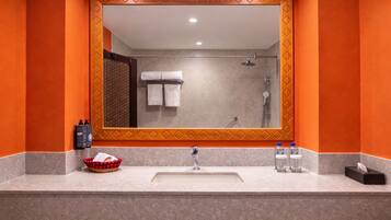 A bathroom with a large mirror, a sink, and a shower.
