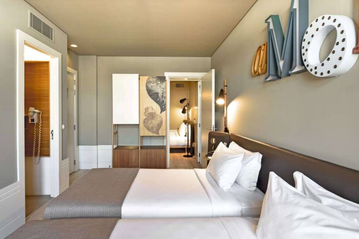 Une chambre d’hôtel moderne avec un grand lit, un bureau et un grand élément décoratif mural.
