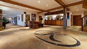 Eine großzügige Lobby mit einer Rezeption, Holzbalken und einem Fliesenboden mit dekorativem Muster.