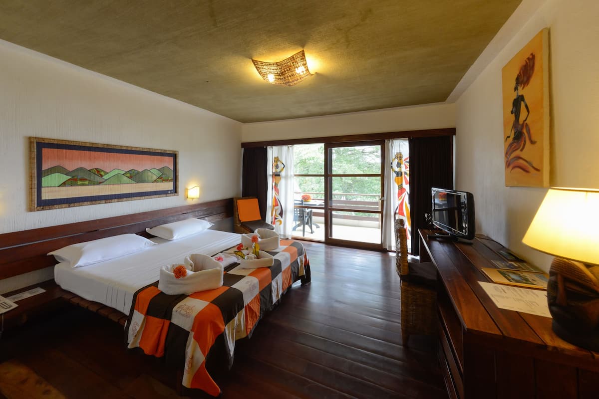 Une chambre d’hôtel avec un grand lit, un bureau avec une lampe, une télévision et un tableau au mur.