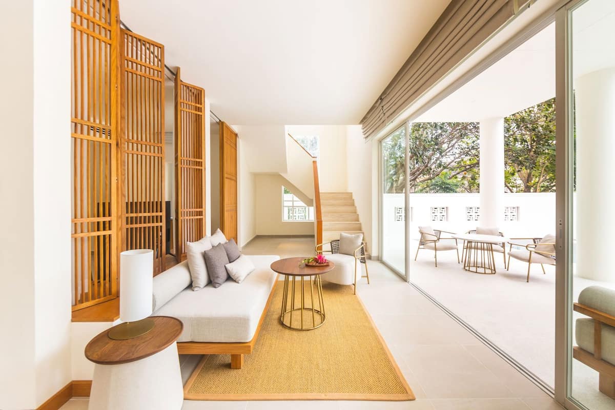 A modern interior with a sofa, a small round table, and a staircase leading to an outdoor area with a dining set.