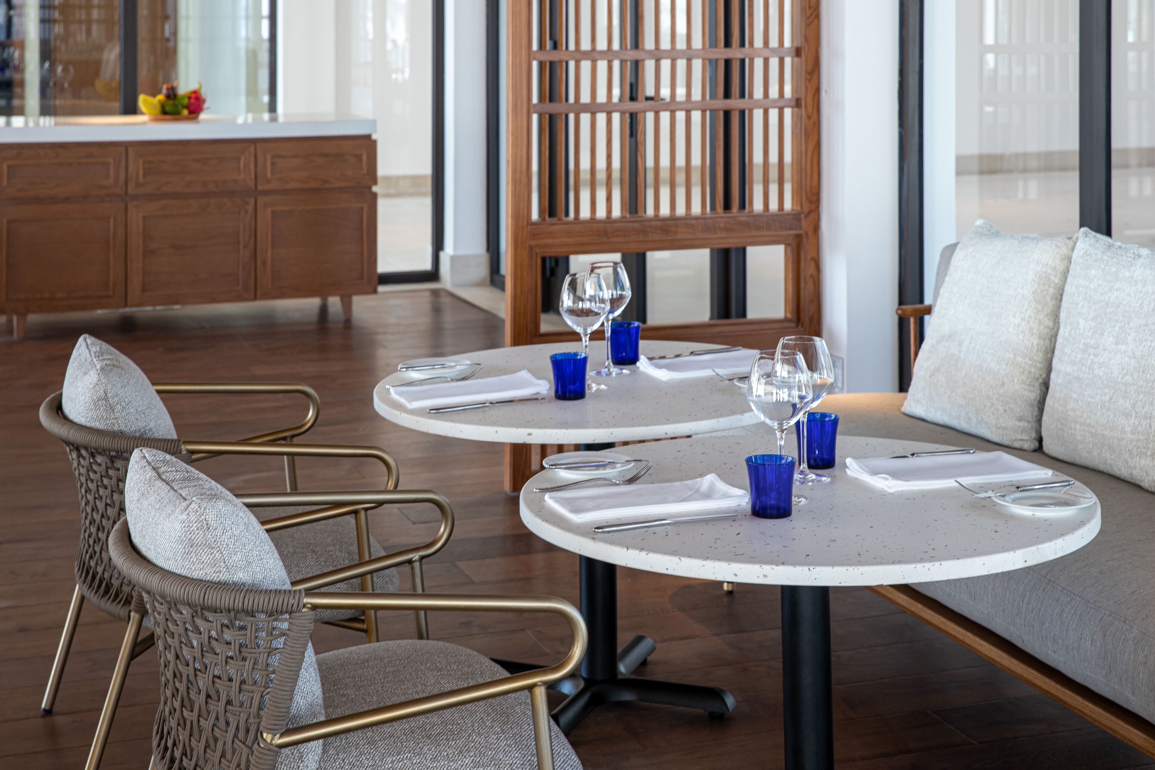 A dining area with round tables, wicker chairs, and a sofa.
