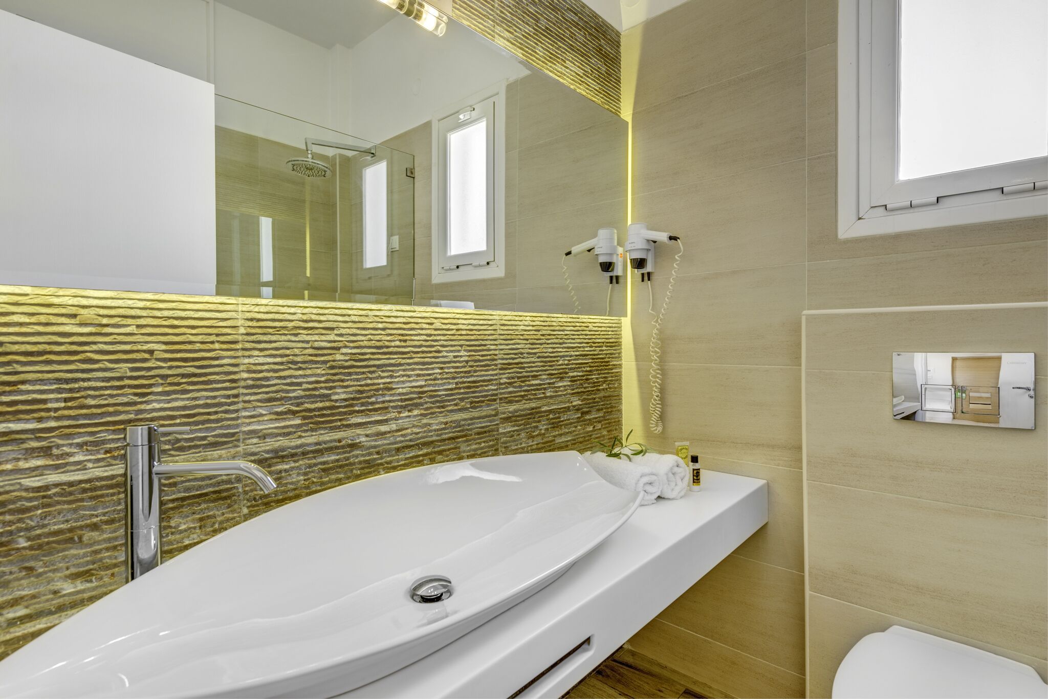 Une salle de bain moderne dotée d’une grande baignoire, d’une douche à parois de verre et d’un miroir agrémenté d’un revêtement mural texturé.