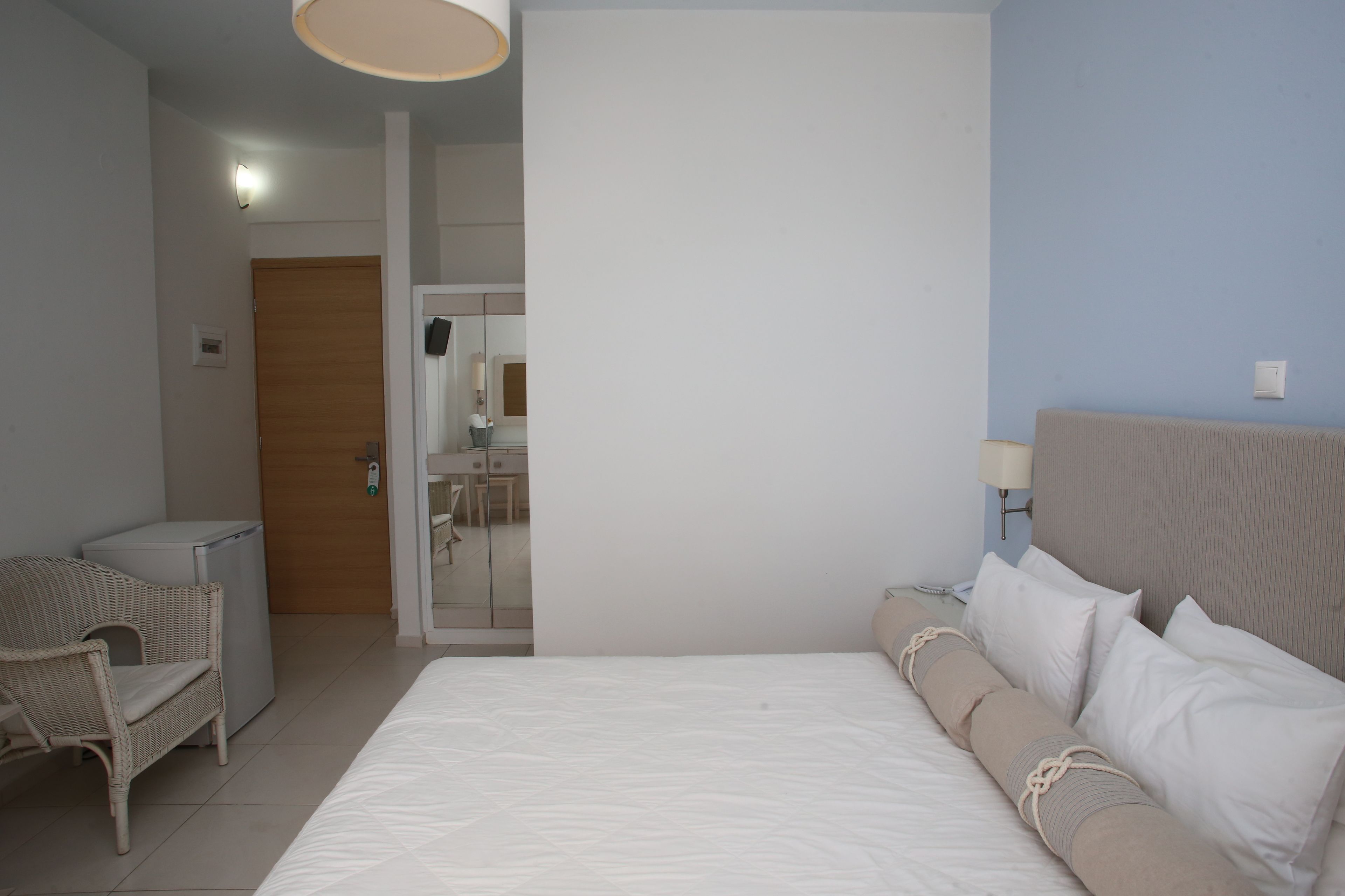 Ein Hotelzimmer mit einem Bett, einem Sessel, einem Schreibtisch, einer Lampe und einer Tür zu einem Badezimmer.