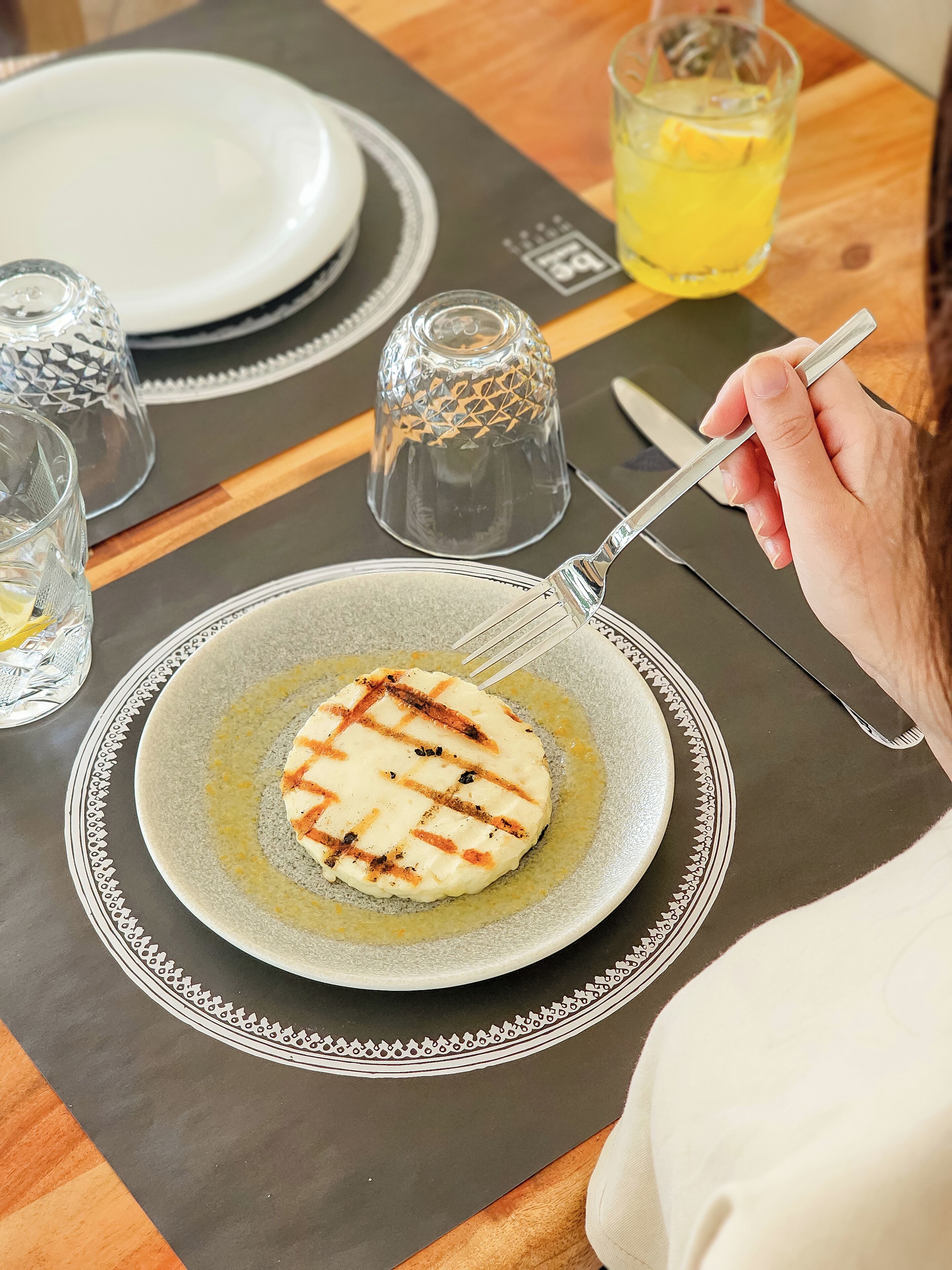 Een bord met gegrild eten, een glas met een citroenpartje en een zoutvaatje op een tafel.