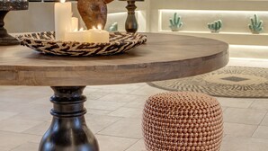 Un intérieur moderne avec une table ronde, des bougies, des sculptures de cactus décoratives et un tapis à motifs.