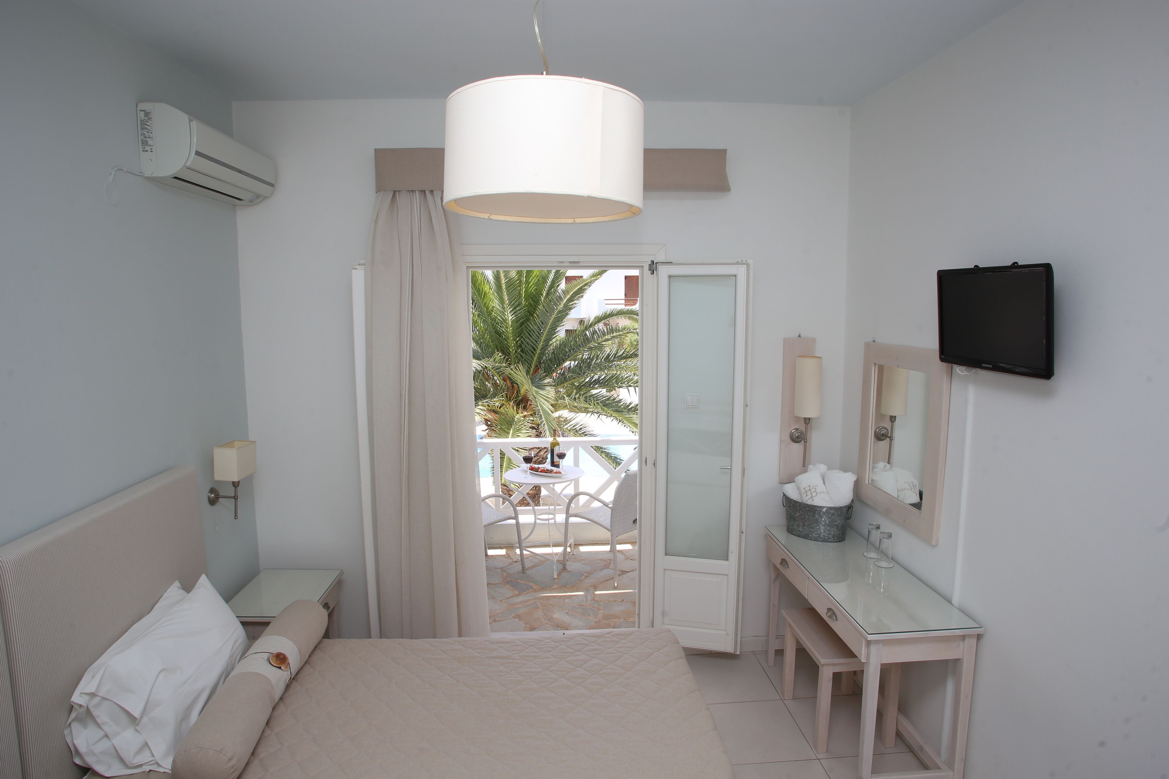 Una habitación de hotel con cama, mesita de noche y baño con espejo y lavabo.
