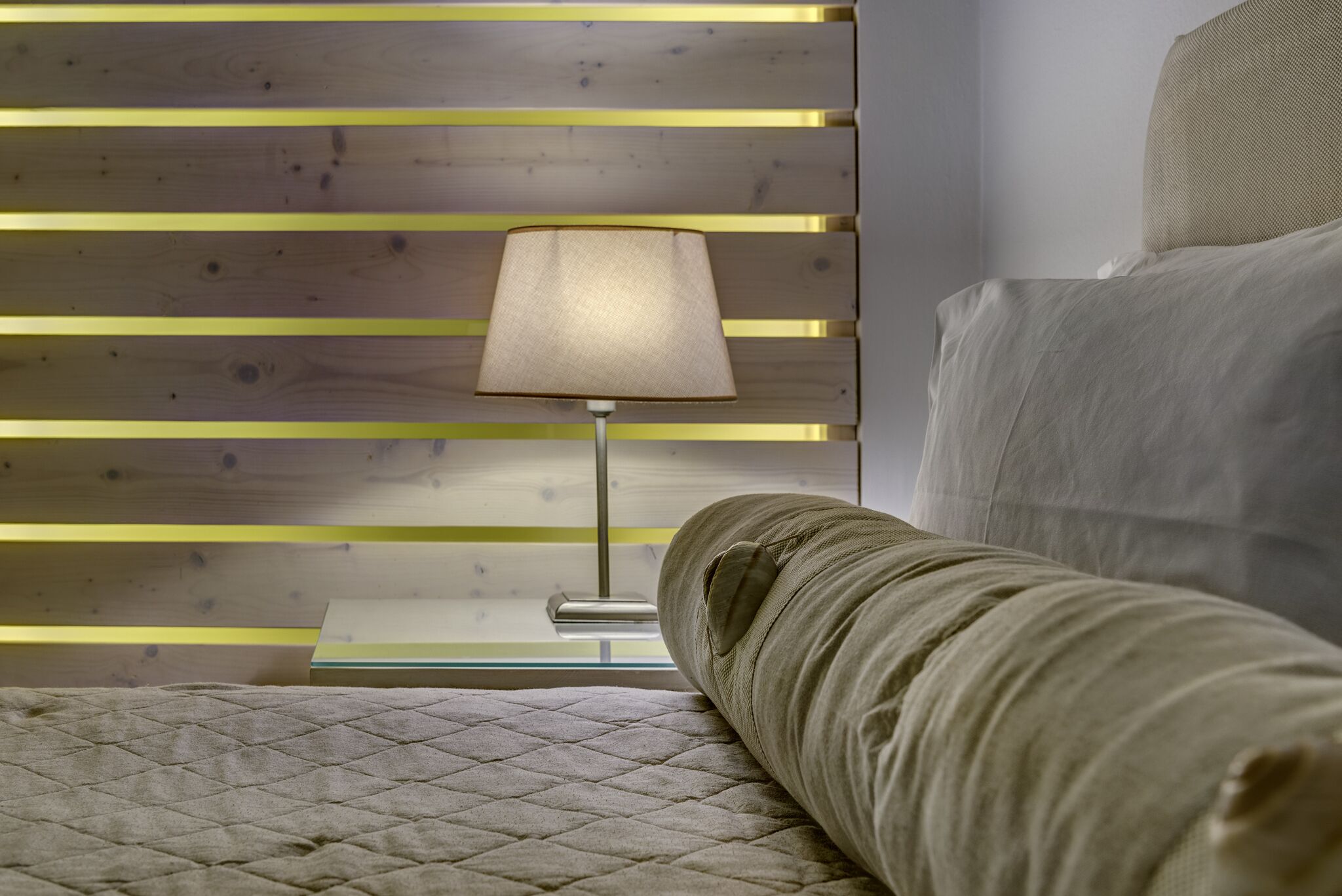 Una cama con un edredón acolchado y una lámpara de noche en la mesita.