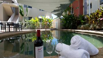 Zona de piscina con una botella de vino, dos copas y una toalla.